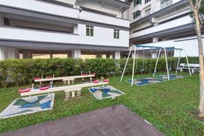 Um pátio com balanço, gangorra e uma piscina pequena.