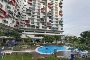 Um edifício residencial alto com piscina e área de estar ao ar livre.