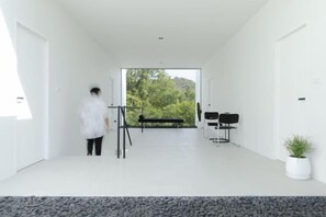 Un intérieur moderne au design minimaliste, comprenant une grande fenêtre, un coin salon et une plante en pot.