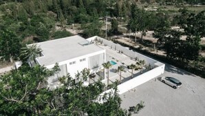 Ein modernes Gebäude mit flachem Dach, einem Swimmingpool und einem Parkplatz.