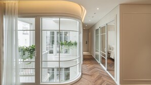 Et moderne interiør med en buet glasbalkon, trægulv og udsigt ud