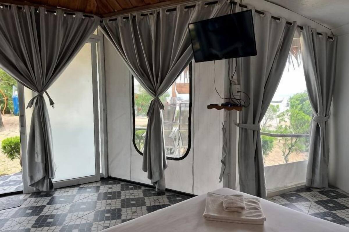 A room with a bed, curtains, a television, and a window with a view.