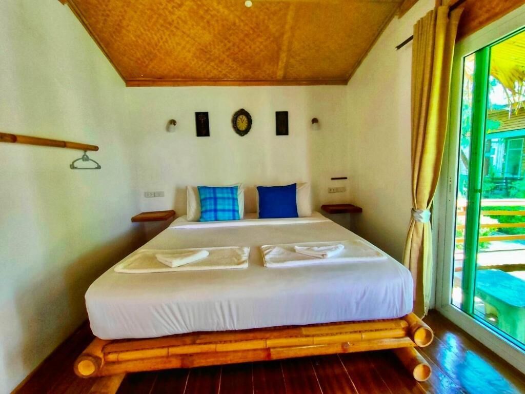 Una cama bien tendida con sábanas blancas y almohadas azules, un cabecero de madera y suelo de madera.