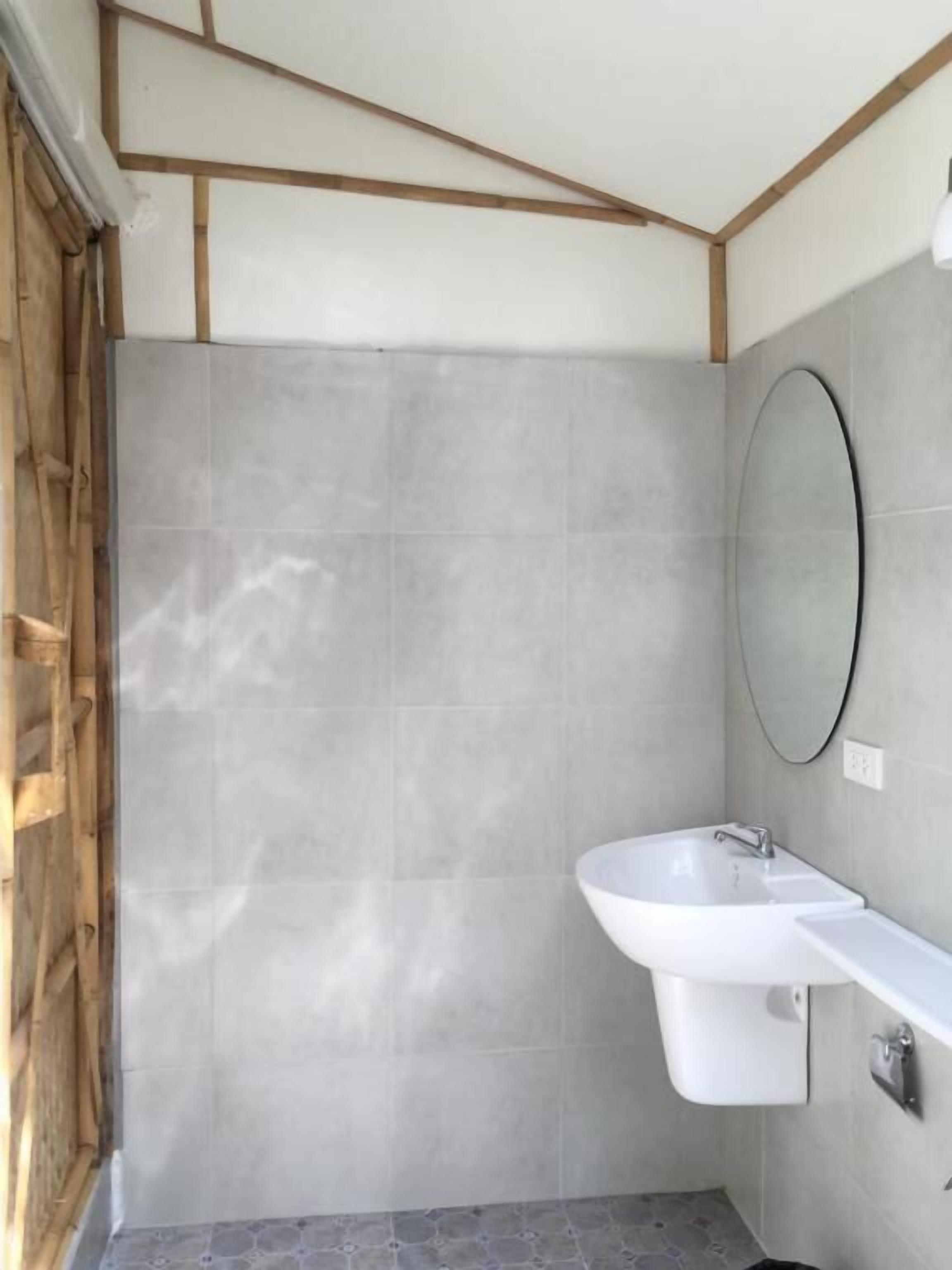 A bathroom with a large mirror, a sink, and a shower area.