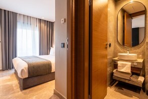 Ein Hotelzimmer mit Bett, Bad mit Waschbecken und Spiegel sowie Blick aus dem Fenster.