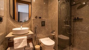 A modern bathroom with a round mirror, a sink, a toilet, and a glass-enclosed shower. - Casablanca Maarif City Center (Casablanca)