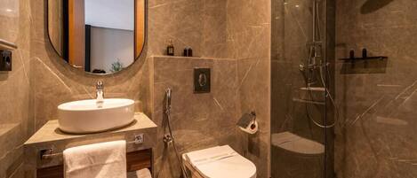 A modern bathroom with a round mirror, a sink, a toilet, and a glass-enclosed shower.