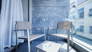 A balcony with two chairs and a small table, a view of a building, and a curtain. - Casablanca Maarif City Center (Casablanca)