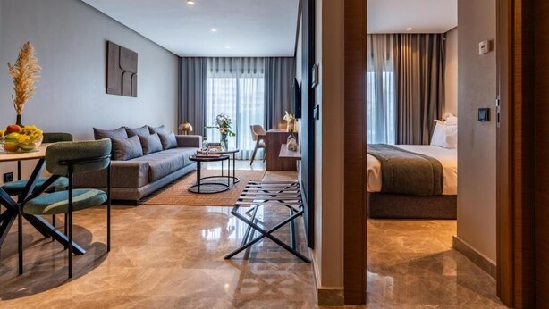 A modern hotel room with a sofa, a dining table, and a bed. - Casablanca Maarif City Center (Casablanca)