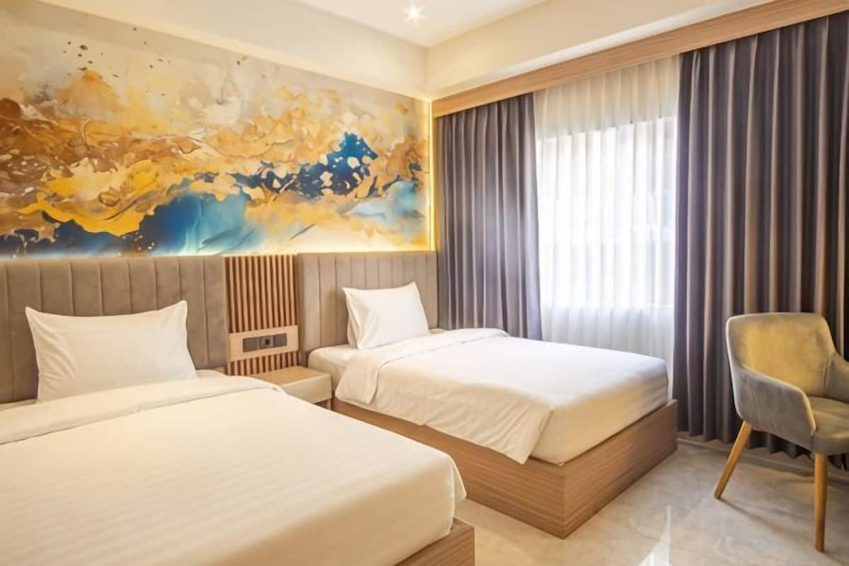 A hotel room with two beds, a large abstract painting, a window with curtains, and a chair.