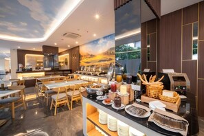 A modern breakfast area with a buffet setup, including various food items and a coffee machine. - Grand Altuz Yogyakarta (Depok)