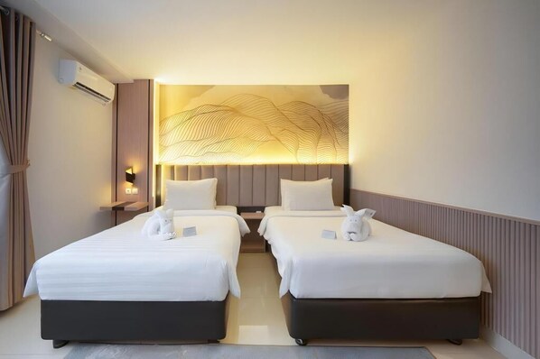 A hotel room with two beds, a wall-mounted air conditioner, and a decorative light fixture.