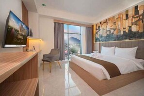 Una camera d'albergo con un letto, una scrivania, una sedia, un televisore e un'ampia finestra.