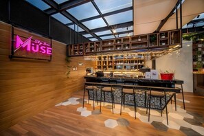 A bar area with a neon sign, wooden shelves, and a bar counter. - Grand Altuz Yogyakarta (Depok)