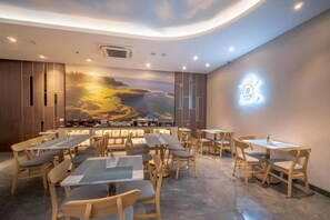 A restaurant with a mural of a sunset landscape, wooden furniture, and a logo on the wall. - Grand Altuz Yogyakarta (Depok)