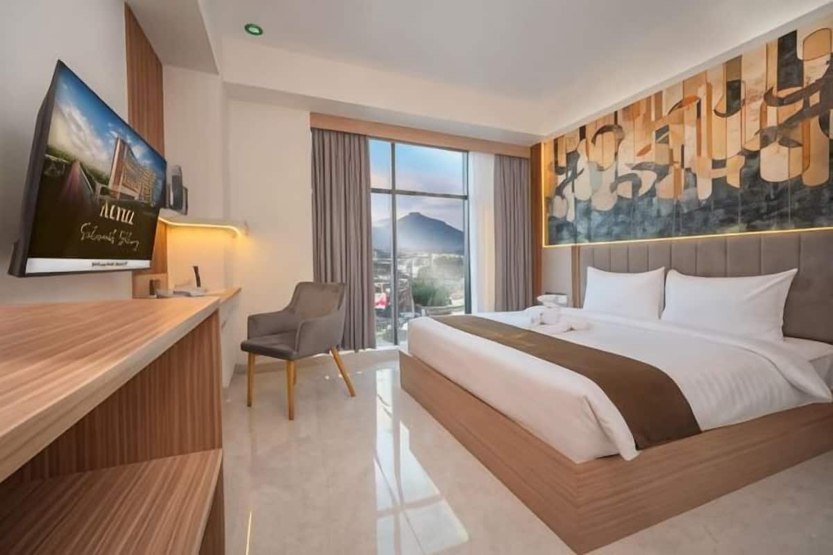 A hotel room with a bed, a desk, a chair, a television, and a large window.