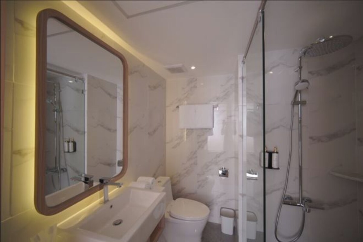 A modern bathroom with a marble sink, a toilet, and a glass-enclosed shower.