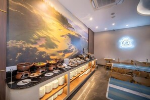 A buffet setup with a variety of dishes and a large mural on the wall.