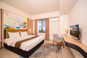 A hotel room with a bed, a desk, a chair, a painting, and a television. - Grand Altuz Yogyakarta (Depok)