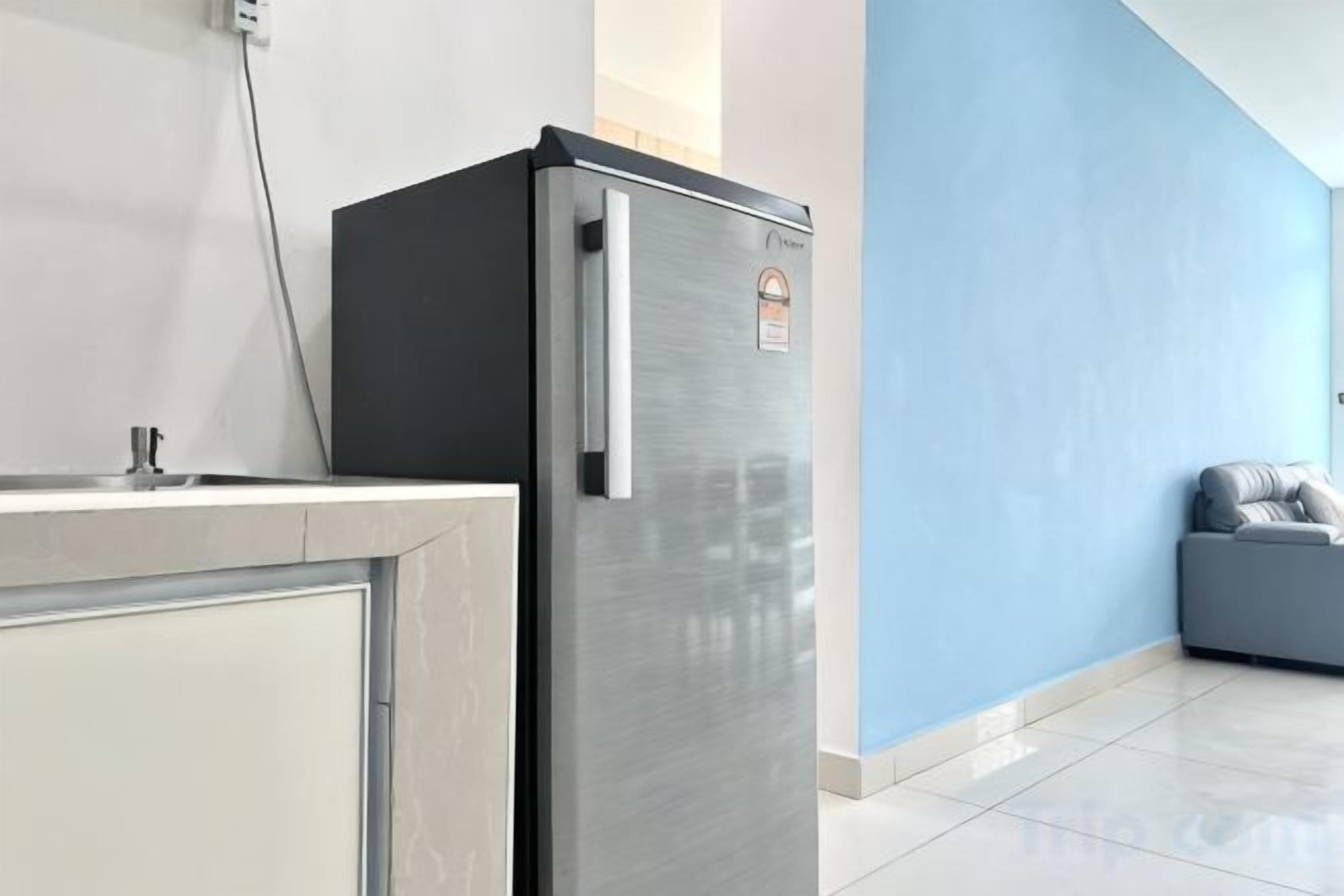Cozinha com geladeira de aço inoxidável, pia e parede azul.