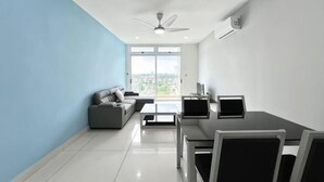 A modern living room with a sofa, coffee table, TV, and a dining area with chairs and a table. - KSL D'Esplanade 2Bedrooms 7-8pax Shopping Heaven (Johor Bahru)