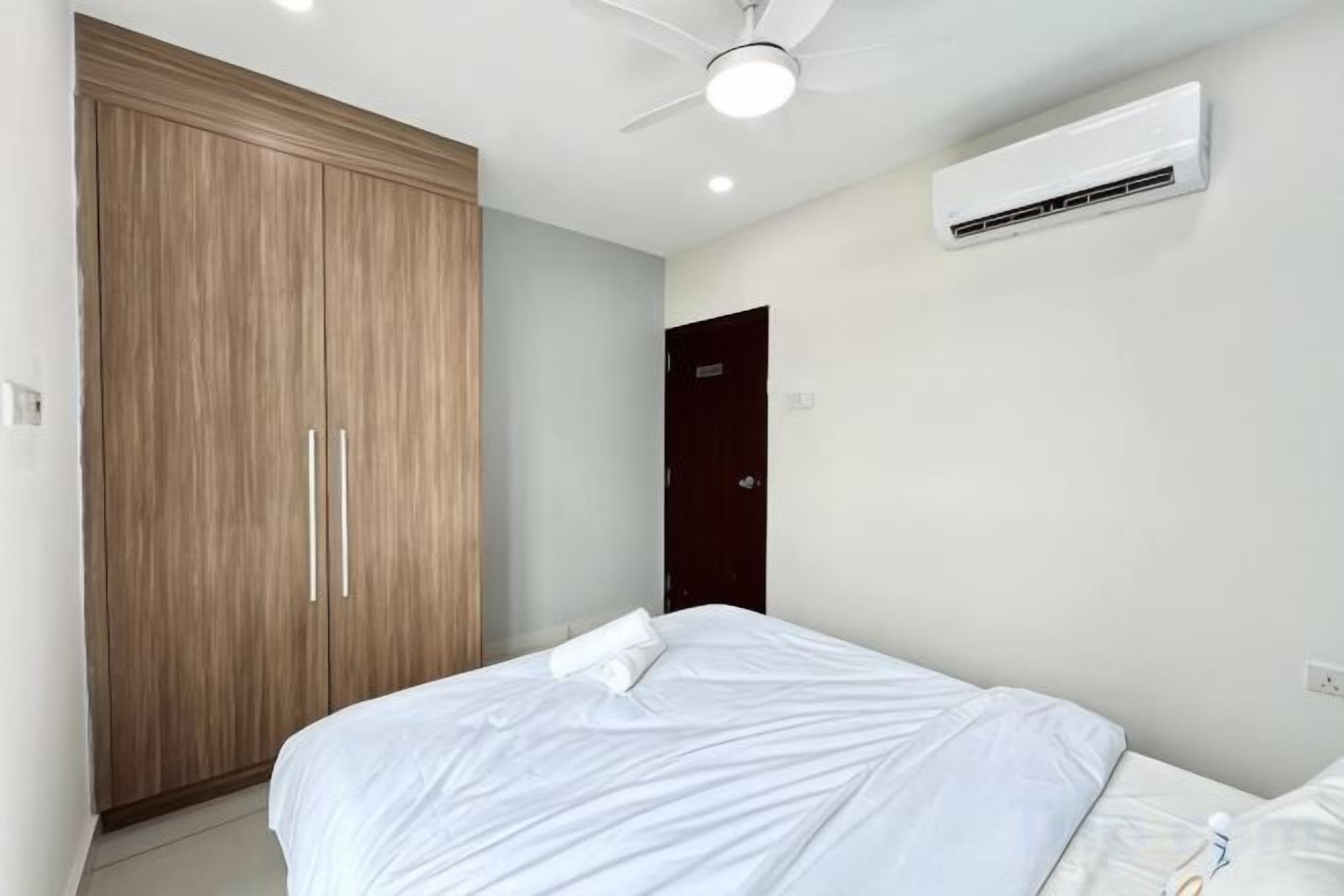 Un dormitorio con cama, armario, ventilador de techo y aire acondicionado.