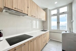A modern kitchen with a white countertop, wooden cabinets, a built-in stove, and a window with a view.
