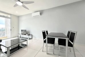 Ein modernes Zimmer mit Esstisch, Stühlen, einem Fernseher und Deckenventilator.