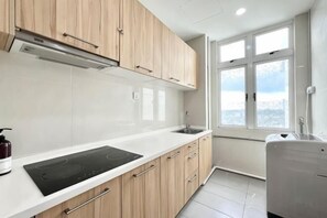 A kitchen with wooden cabinets, a white countertop, a built-in stove, and a window with a view. - KSL D'Esplanade 2Bedrooms 7-8pax Shopping Heaven (Johor Bahru)