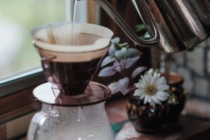 Une machine à café dotée d’une verseuse en verre transparent et d’un bac d’égouttement en métal.