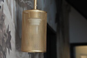 A cylindrical, perforated metal light fixture hanging from a ceiling. - Haheng House (Bangkok)