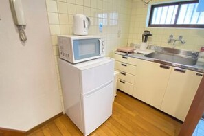 A compact kitchen with a microwave on a small refrigerator, a sink, and a window above the sink. - AkiraHome Tsutenkaku West -THE CALM HOUSE- (Osaka)