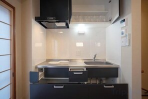 A compact kitchen with a stove, sink, and cabinets. - HAKUKOU UROMURO (Kyoto)