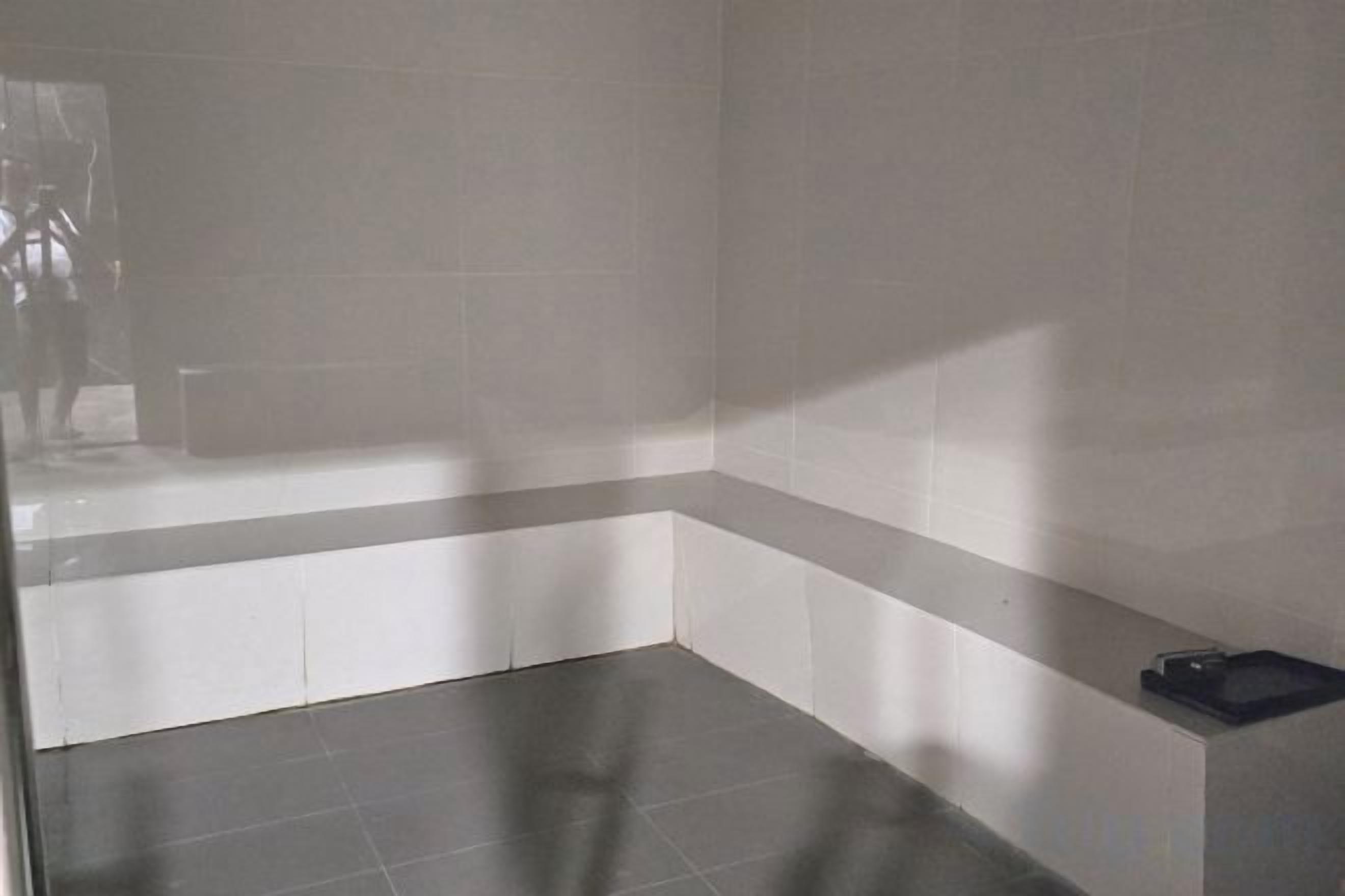 A bathroom with a bathtub, a shower area, and a small shelf with a black object on it.