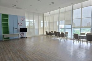 A spacious room with a long table and chairs, large windows, and a green shelving unit. - Seaview-Pinetree Marina Resort 2BR [Puteri Harbour] - 5 mins to Legoland (Iskandar Puteri)
