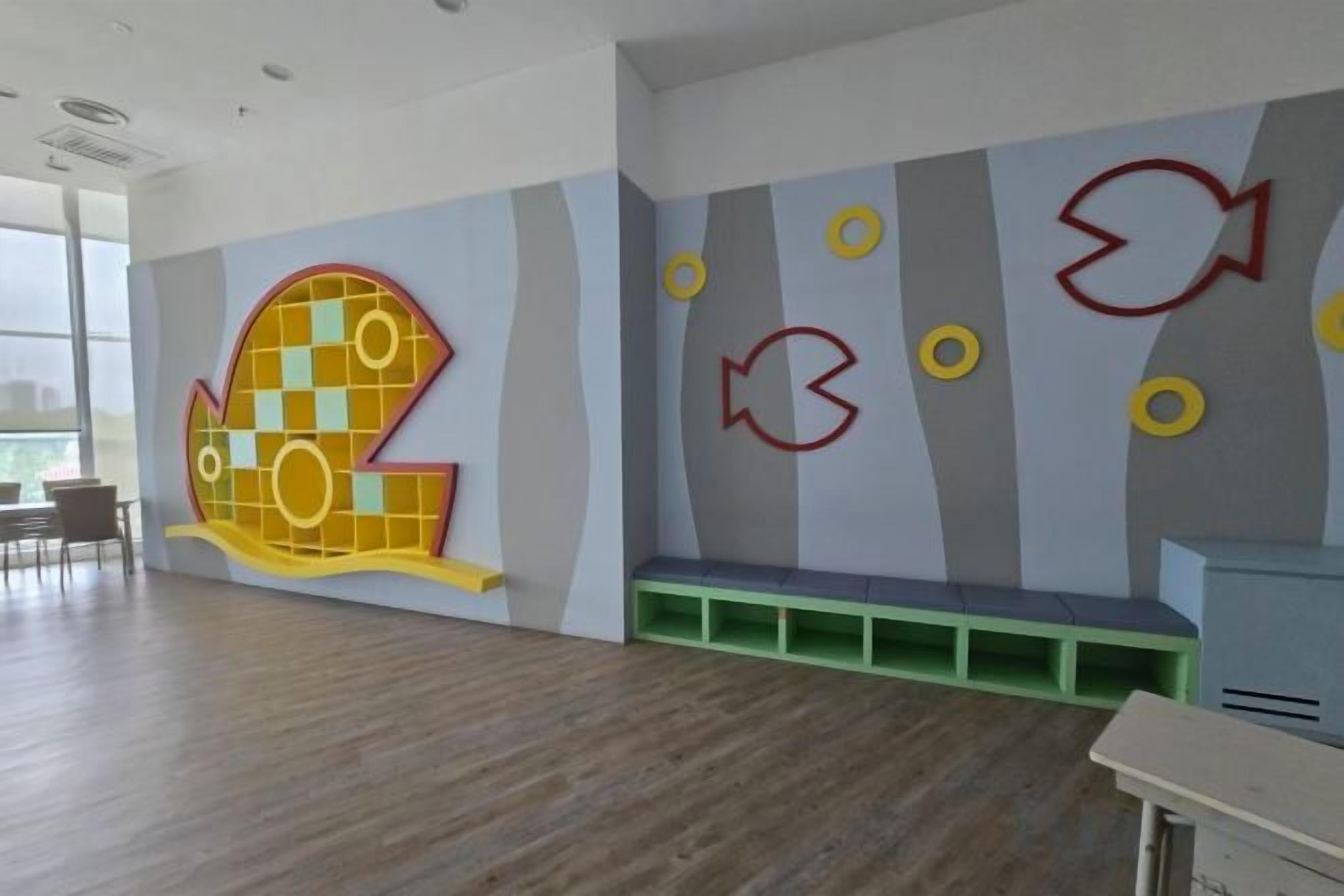 Une pièce décorée d’une grande fresque représentant des poissons, avec un banc et un bureau.