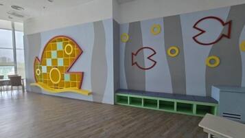 Une pièce décorée d’une grande fresque représentant des poissons, avec un banc et un bureau.