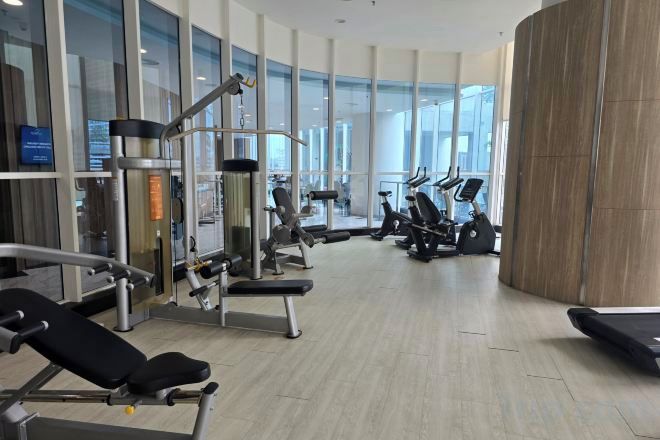 Ein Fitnessstudio mit verschiedenen Trainingsgeräten, darunter Laufbänder und Kraftgeräte, mit modernem Ambiente und großen Fenstern.