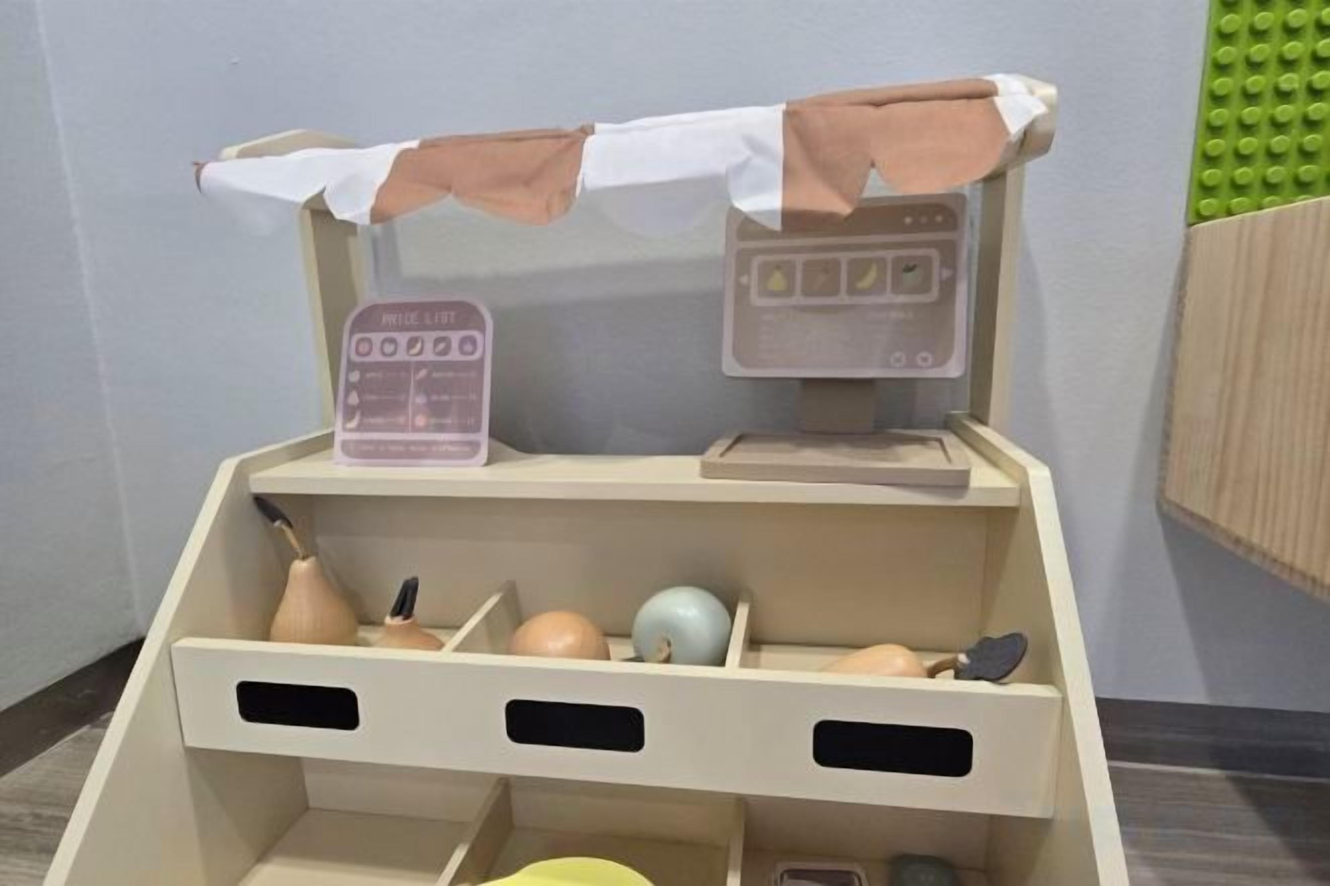 A toy kitchen setup with a price list, a cash register, and various kitchen utensils.