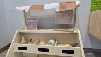 A toy kitchen setup with a price list, a cash register, and various kitchen utensils.