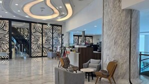 A modern lobby with a marble floor, a reception desk, and seating areas. - Seaview-Pinetree Marina Resort 2BR [Puteri Harbour] - 5 mins to Legoland (Iskandar Puteri)