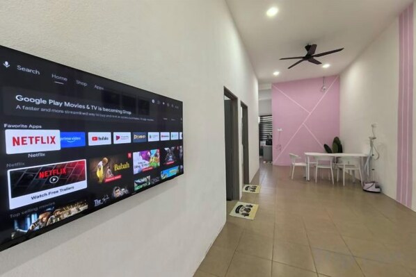 A hallway with a large digital screen displaying a Google Play Movies & TV interface. - Homestay Sungai Karangan Near Inokom (Padang Meha)