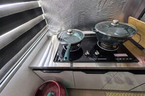 A kitchen with a stove, two pots, and a red gas cylinder. - Homestay Sungai Karangan Near Inokom (Padang Meha)