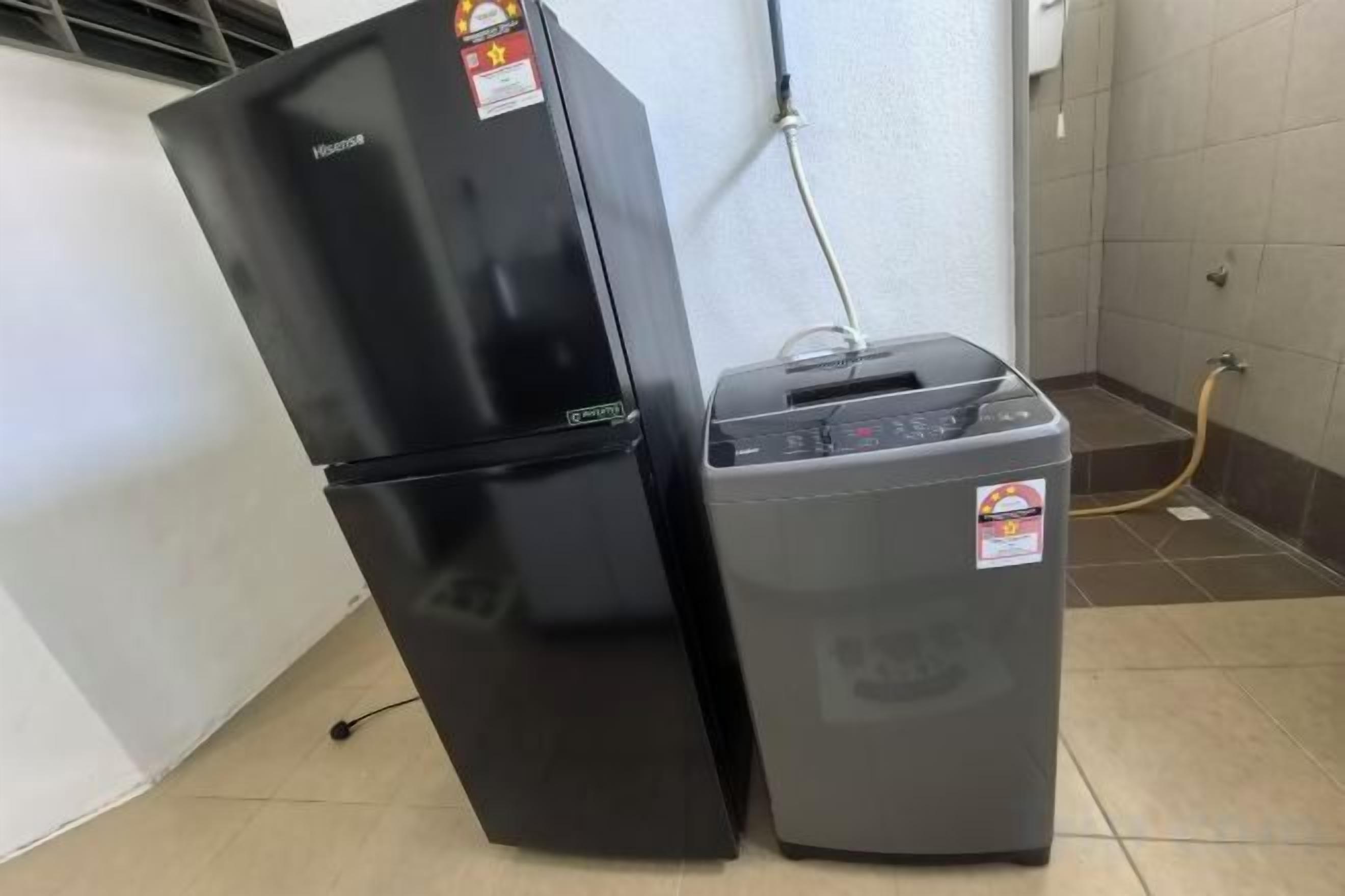 Een zwarte koelkast en een grijze wasmachine staan naast elkaar in een kamer met betegelde vloer.