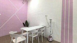 A room with a white table and chairs, a pink wall, and a small plant. - Homestay Sungai Karangan Near Inokom (Padang Meha)