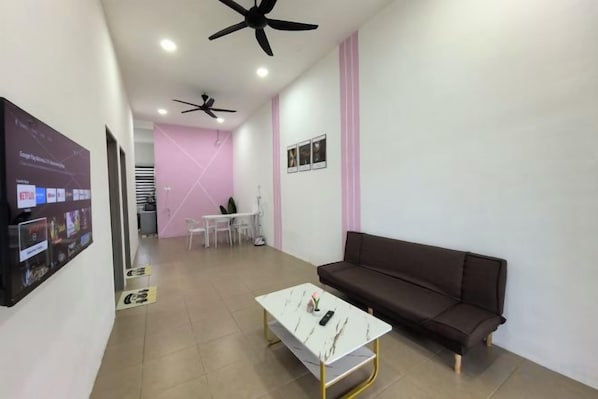 A modern living room with a brown sofa, a white coffee table, and a ceiling fan. - Homestay Sungai Karangan Near Inokom (Padang Meha)