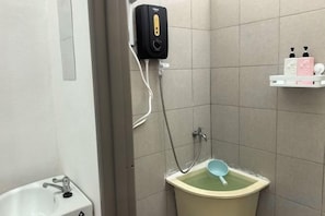 A bathroom with a toilet, a bidet, and a soap dispenser on a shelf. - Homestay Sungai Karangan Near Inokom (Padang Meha)