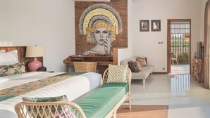 Ένα δωμάτιο ξενοδοχείου με ένα κρεβάτι, ένα γραφείο, μια καρέκλα, έναν καναπέ και μια τοιχογραφία στον τοίχο.