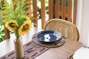 A dining table with a plate, a vase with flowers, and a chair. - Dijero at Umah Bali (Bali)