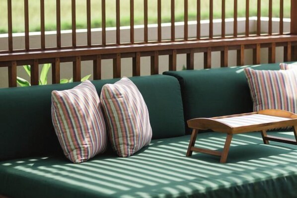 A green sofa with striped pillows and a wooden side table. - Dijero at Umah Bali (Bali)
